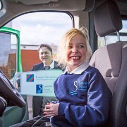 Child laughing behind the wheel of a minibus