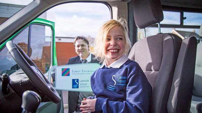 Child laughing behind the wheel of a minibus