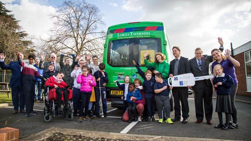 Group photo of all the children and stakholders posing infront of a green minibus