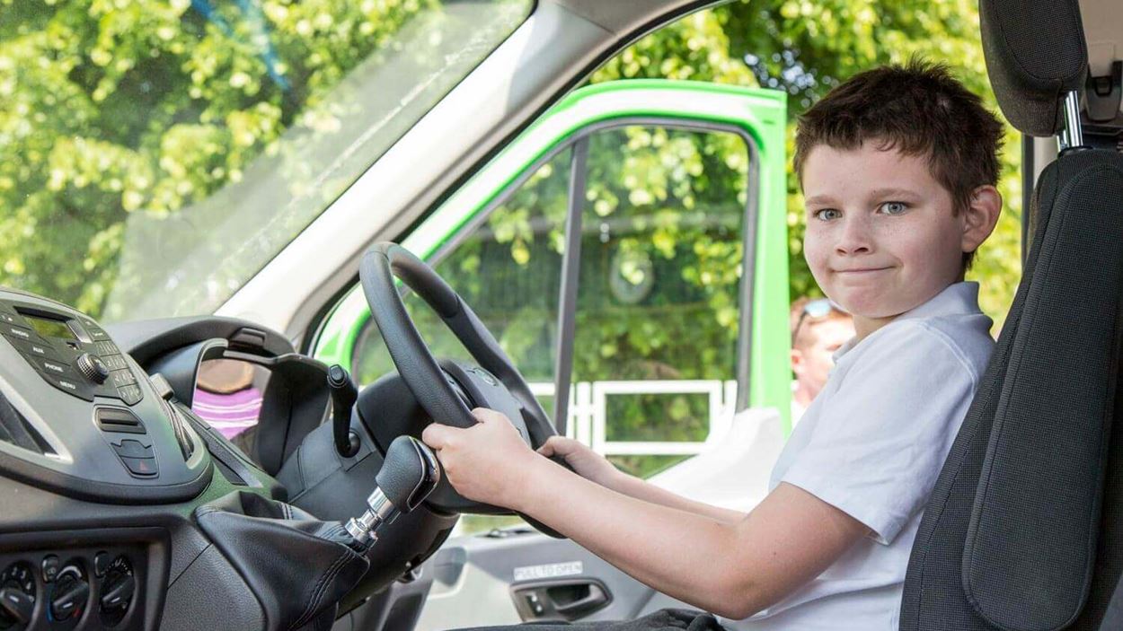 Little boy with both hands on the minibus wheel