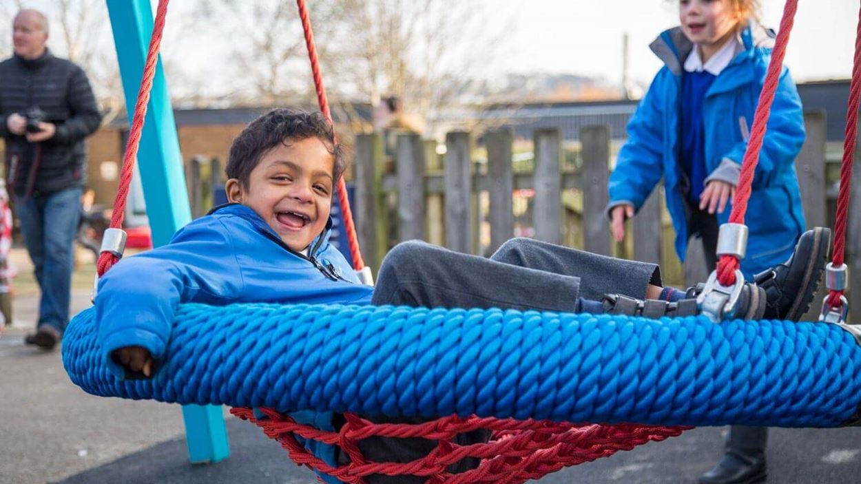 Little boy laughing while on a swing