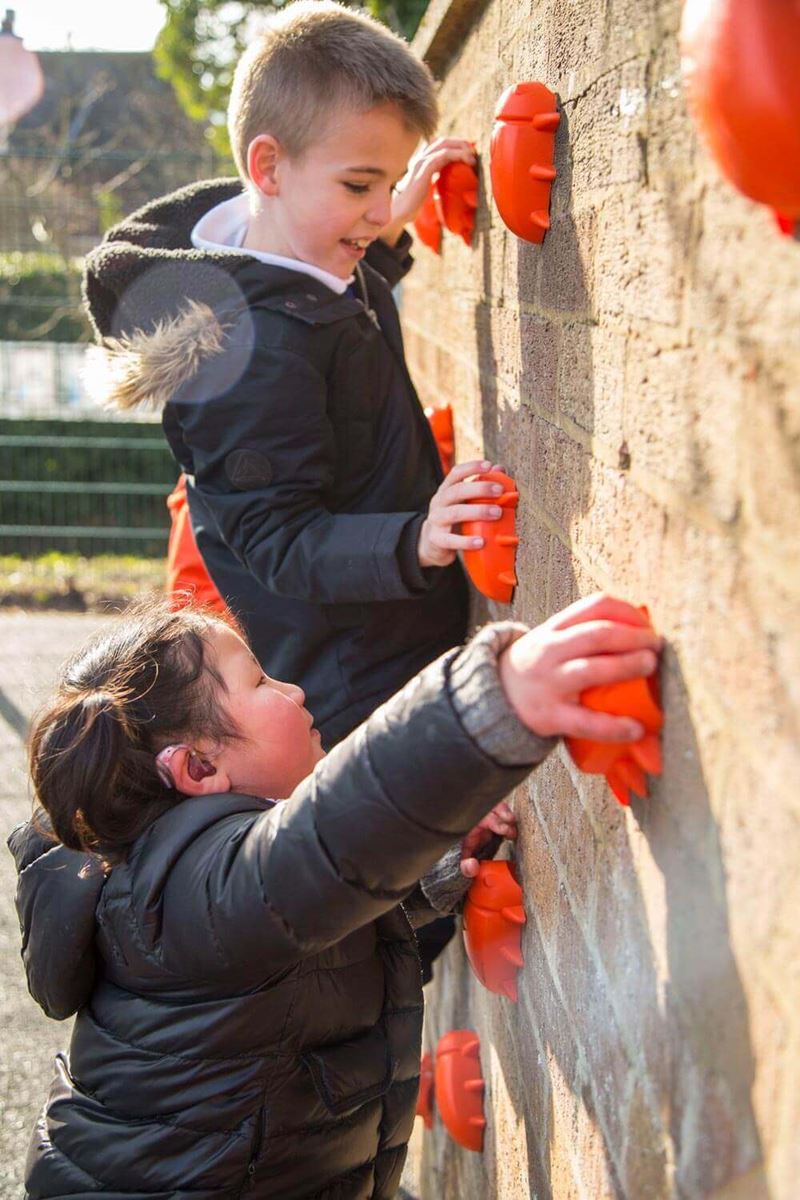 Little boy scaling a rock climbing wall