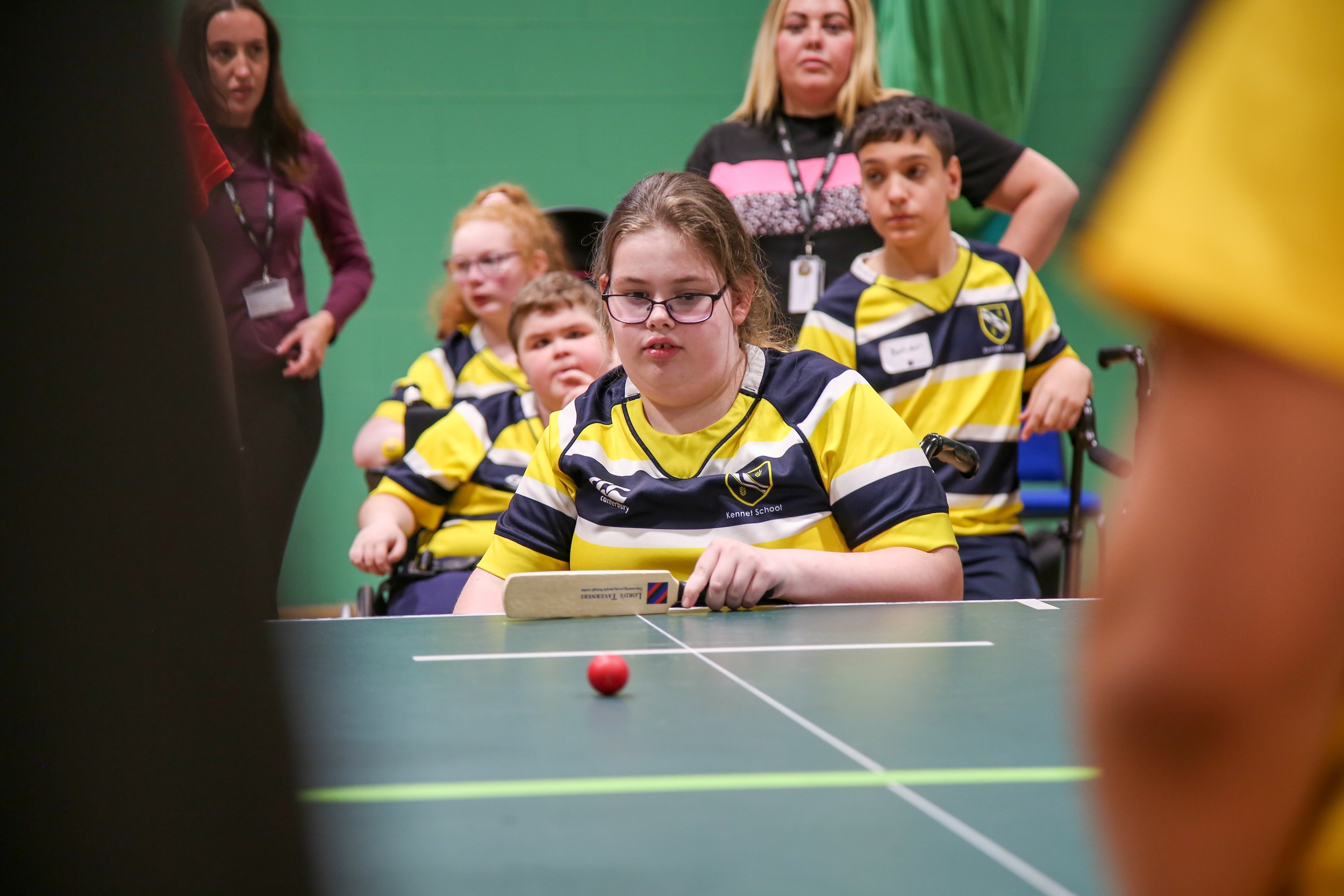 Kennet School participant preparing to bat in table cricket with her teammates and staff from her school behind her